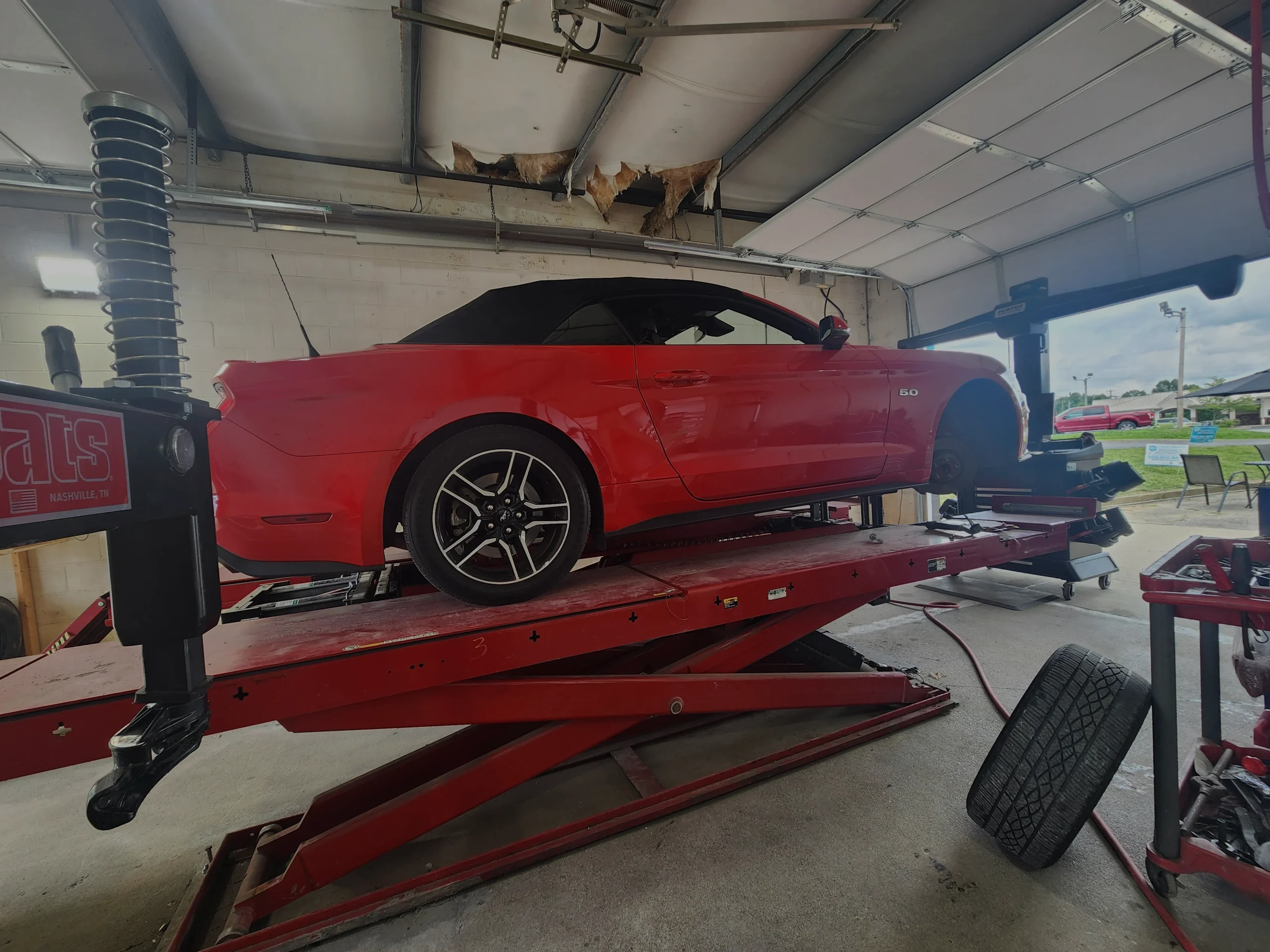 Red customer vehicle receiving professional automotive service at Supreme Tires in Floyds Knobs, Indiana.